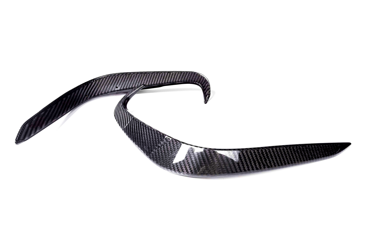 Two curved carbon fiber pieces are positioned parallel on a white background, likely automotive parts, showcasing sleek, aerodynamic lines and a glossy finish.