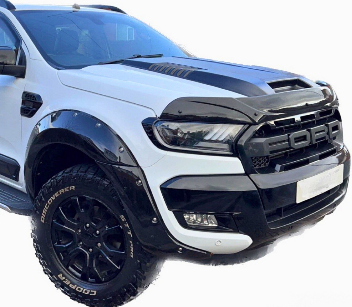 Truck displaying a bold grille with "FORD" lettering, parked. It has a black-and-white color scheme, large rugged tires reading "COOPER DISCOVERER STT PRO," against a plain white background.