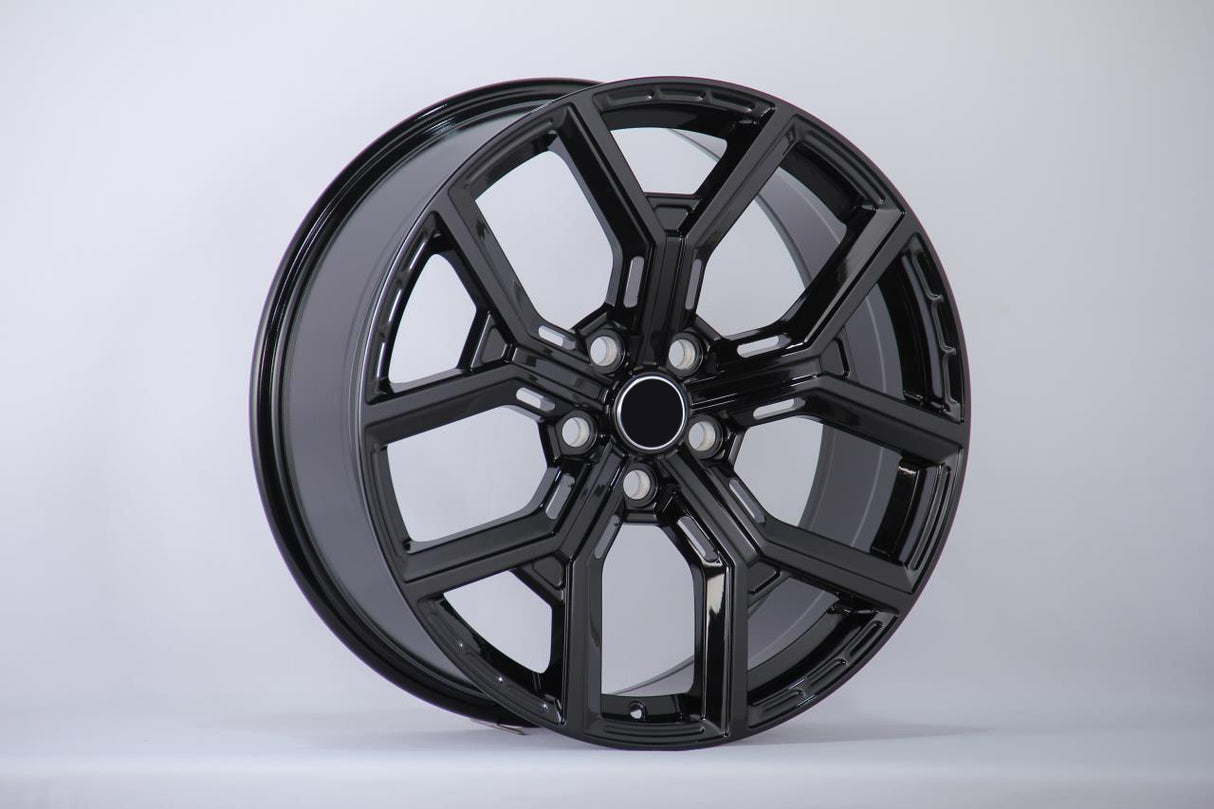 A sleek, glossy black alloy car wheel sits angled, displaying its intricate spoke design against a neutral gray background.