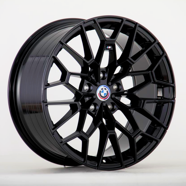 A glossy black alloy wheel with a complex, geometric spoke design; features the BMW emblem at the center, set against a plain white background.