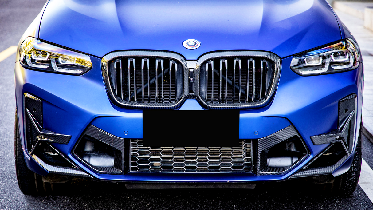 A blue car's front features a modified grille with a smiling logo, surrounded by bright headlights. The vehicle is parked against a blurred urban background.