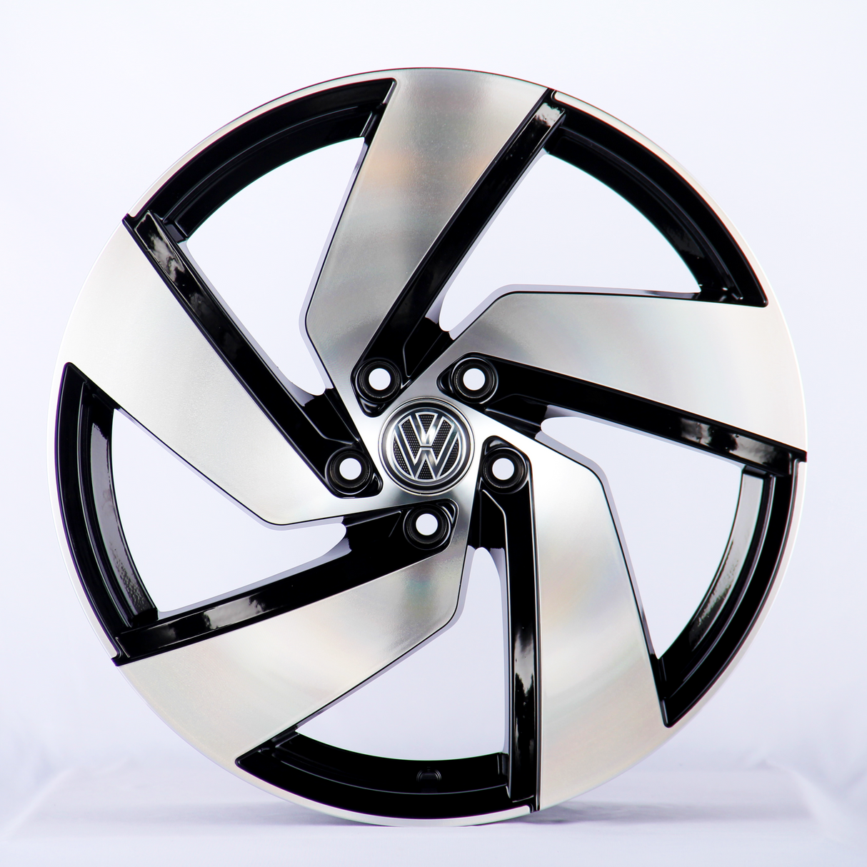 A metallic car wheel rim with a five-spoke design features a central logo containing a "VW" emblem, displayed against a plain white background.