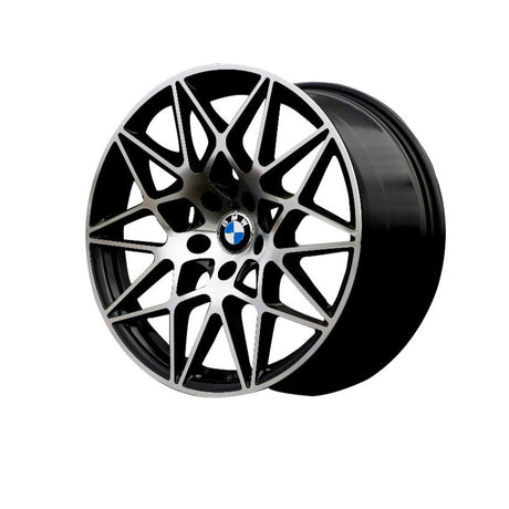 A sleek, intricate multi-spoke BMW car wheel with a central blue and white logo is displayed against a plain white background, emphasizing its geometric design and smooth finish.