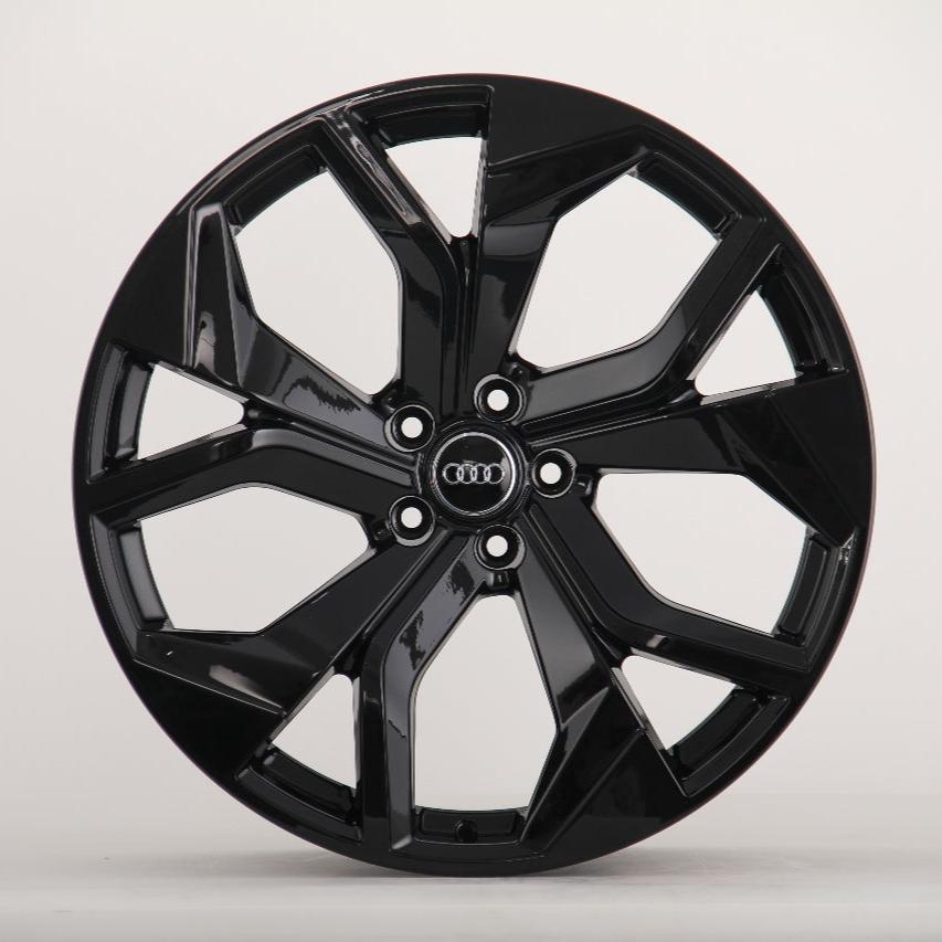 A glossy black car wheel with multiple spokes featuring the Audi logo at its center, displayed against a plain white background.