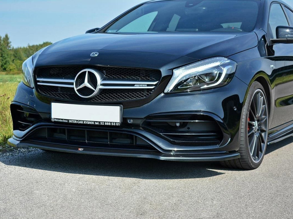 A black Mercedes-Benz car is parked on a road, showcasing its sleek front grille and headlights. Text: "Mercedes-Benz INTER-CAR RYBNIK tel. 32 888 53 01." Grassy fields are in the background.