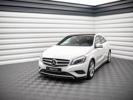 A white Mercedes-Benz car is parked in a modern, grey-tiled showroom with striped white and black walls. The front license plate reads "MAXTON design."