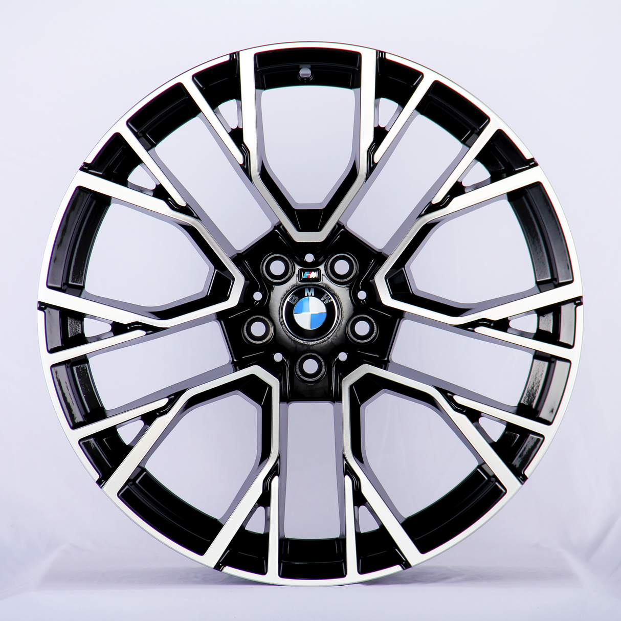 A black and chrome car wheel rim, with intricate geometric patterns, displaying the BMW logo at its center; set against a plain white background.
