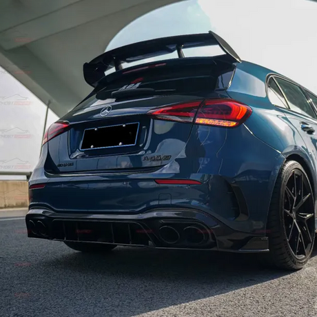 A dark blue Mercedes-AMG A35 car is parked, highlighting its aggressive rear spoiler and quad exhausts. It is positioned under a modern, curved architectural structure.