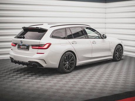 A white BMW station wagon is parked on a checkered floor in a bright, modern showroom. The license plate reads "DARITON DESIGN."