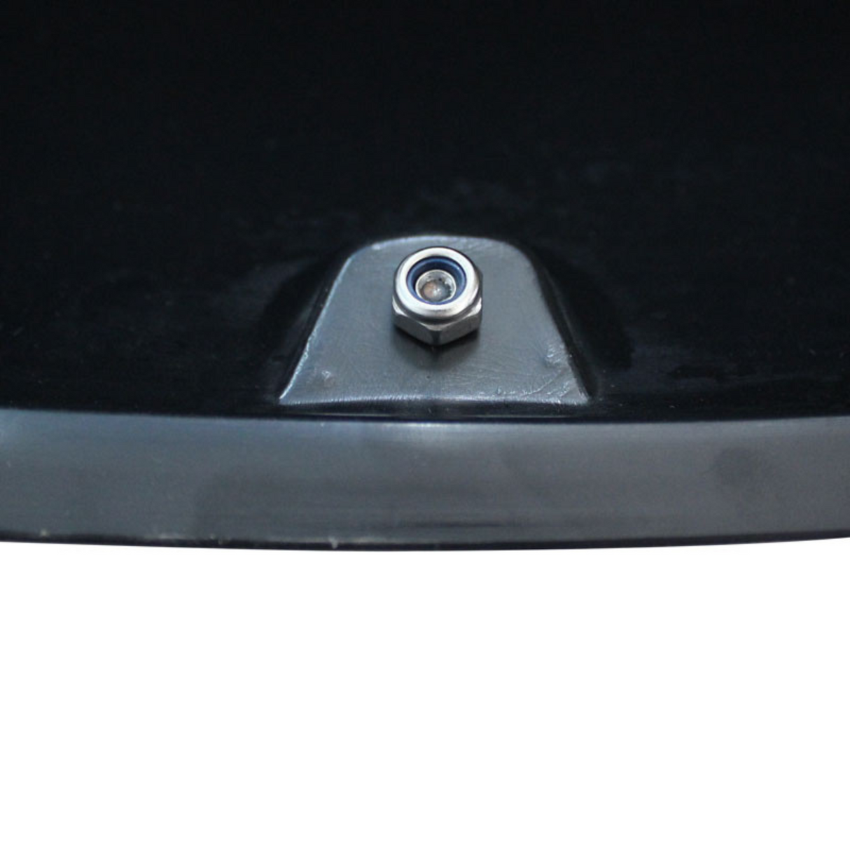 A metal bolt is fixed onto a flat black and gray surface, surrounded by dark background.