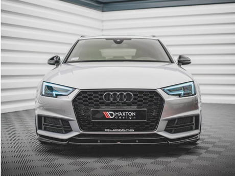 A silver Audi car with illuminated headlights is parked in a tiled, enclosed space. The front license plate reads "MAXTON design" and "quattro" below.