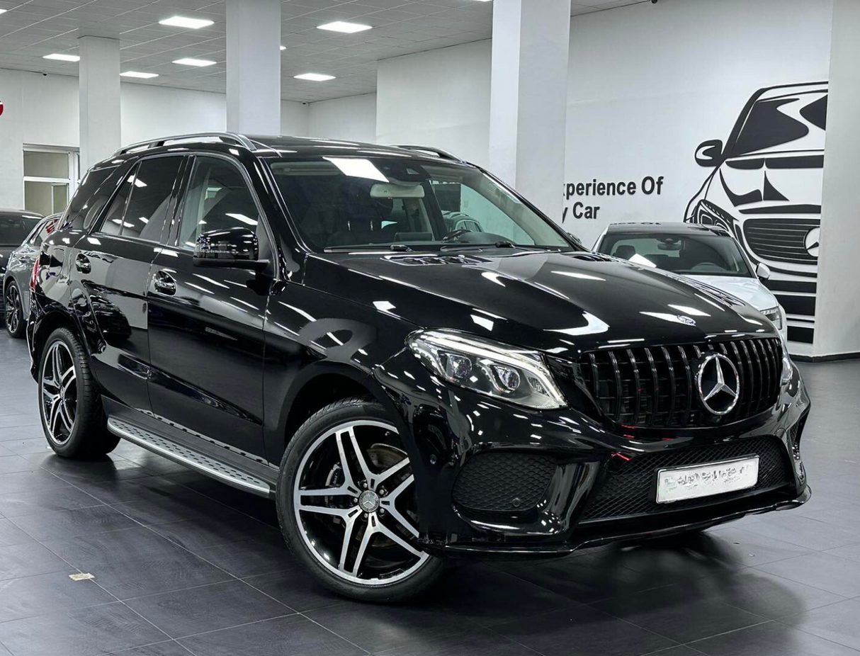 A black SUV is parked indoors, featuring a sleek design and alloy wheels. The setting is a showroom with white walls and a car illustration. Text on the wall reads, "Experience Of Luxury Car."