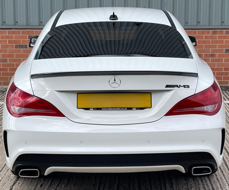 A white Mercedes-Benz AMG car is parked, featuring dual exhausts and tinted windows, against a backdrop of red brick and corrugated metal. Text: "www.mdscarsales.co.uk".