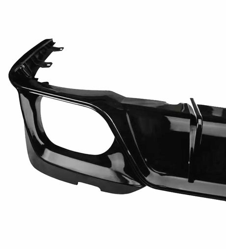 A shiny black car bumper is viewed close-up, displaying a smooth finish and angular design. It is photographed against a plain, white background, highlighting its contours.