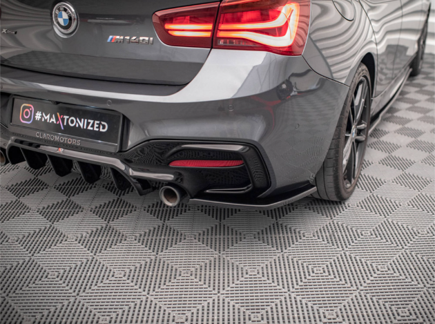 A gray sports car's rear, parked on a textured gray floor with geometric patterns. The license plate reads "# MAXTONIZED CLAROMOTORS" and the brake lights are illuminated within a structured garage setting.