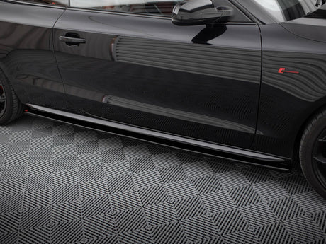 A shiny black car door with reflections parked on a patterned grey floor. The car features a red emblem and sleek design lines.