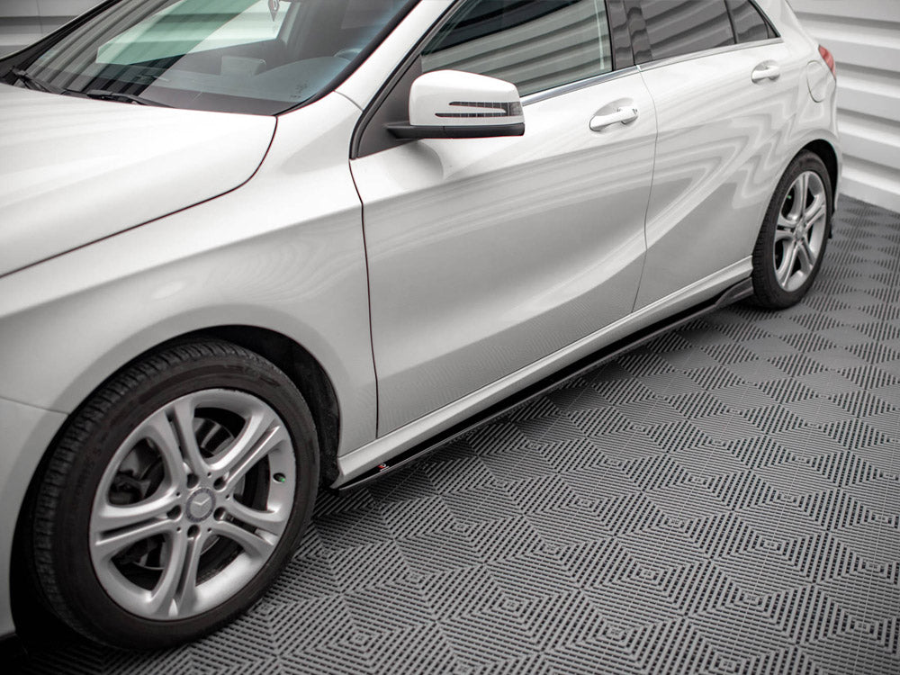 A silver car is parked on a patterned floor, displaying sleek design lines and alloy wheels. The setting has bright lighting and a textured surface, enhancing the vehicle's shine.