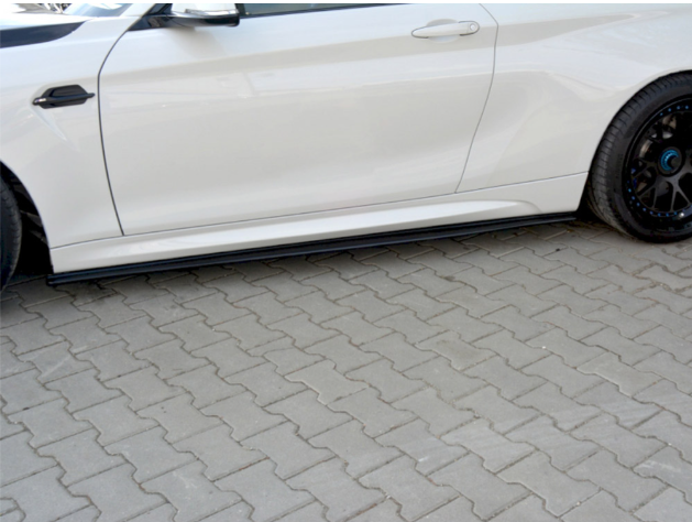 A white car is parked on a paved surface, highlighting its side profile with a sleek design and black wheel. The car's side mirror and door handle are visible.