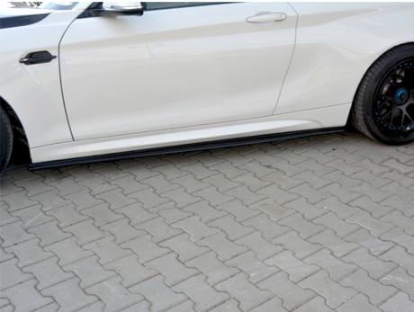 A white car is parked on a paved surface, highlighting its side profile with a sleek design and black wheel. The car's side mirror and door handle are visible.