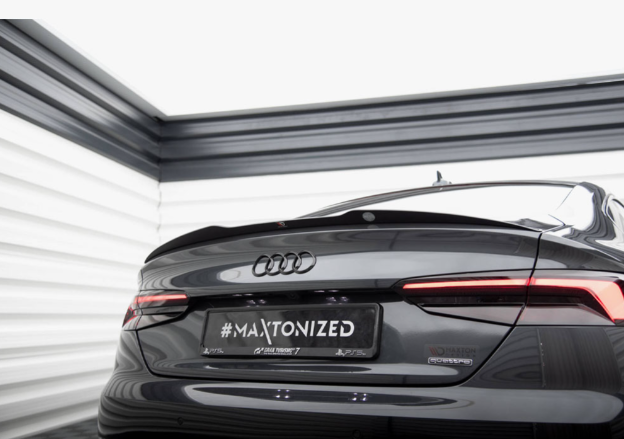 A sleek Audi car is parked in a modern, well-lit showroom. The license plate reads "#MAXTONIZED," and the setting emphasizes the car's glossy finish and streamlined design.