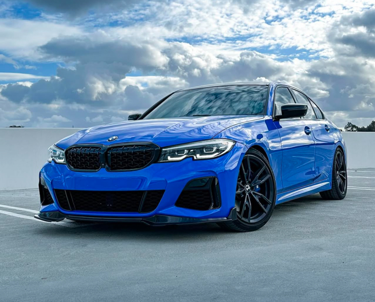 A blue BMW car is parked on a rooftop parking lot, under a cloudy sky with patches of blue.