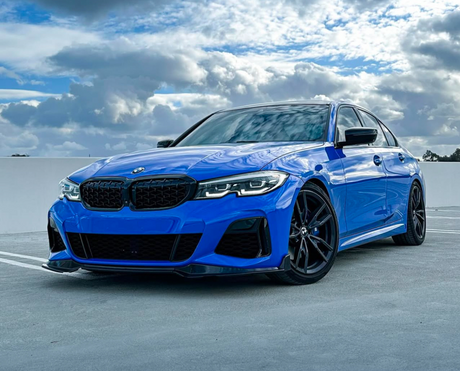 A blue BMW car is parked on a rooftop parking lot, under a cloudy sky with patches of blue.
