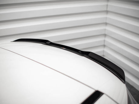 A car roof with a sleek black roof spoiler is parked inside a garage, framed by ribbed metallic walls, adding a modern touch to the minimalistic setting.