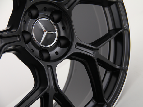 A black metal car wheel with a five-spoke design features a silver star emblem in the center against a plain white background.