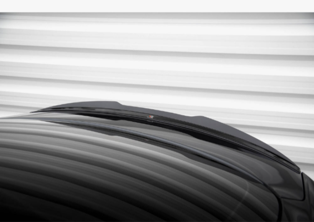 A glossy black car roof appears in front of horizontally striped, blurred white background, with a subtle structure and a small detail on top.