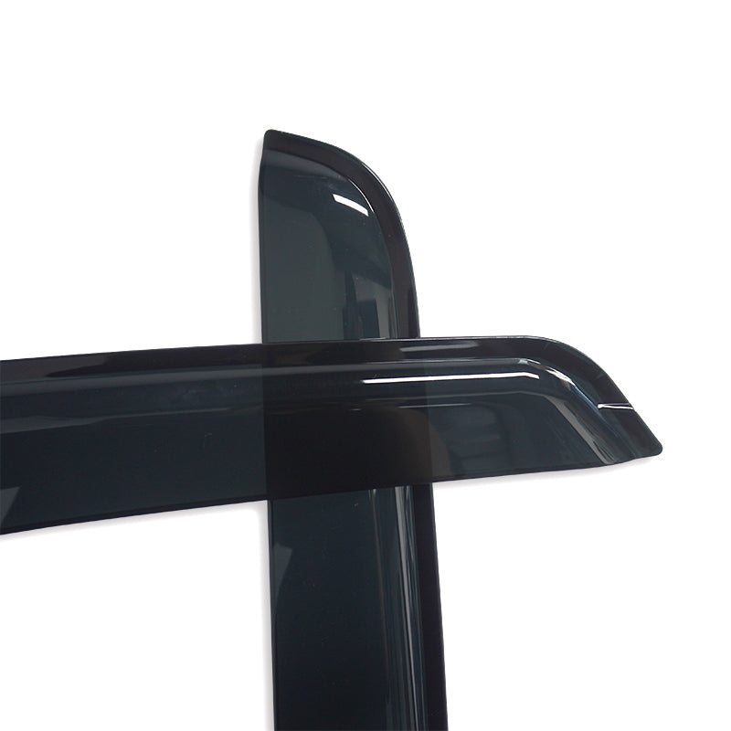 Two dark-tinted, curved plastic car deflectors are crossed over each other, resting on a white surface, showcasing their glossy finish and smooth edges.