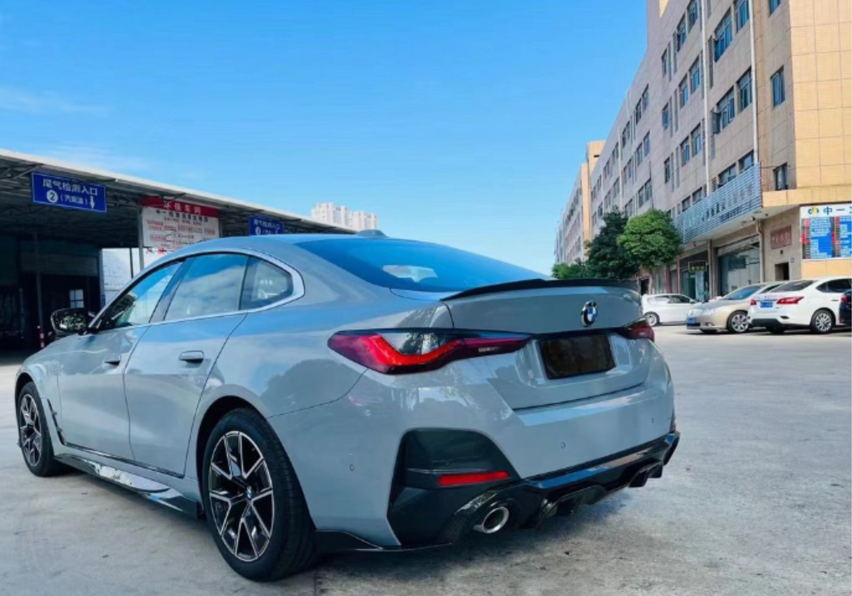 A gray car is parked near a commercial building under a clear sky. Nearby, other vehicles and signs with Chinese text are visible, indicating a bustling urban environment.