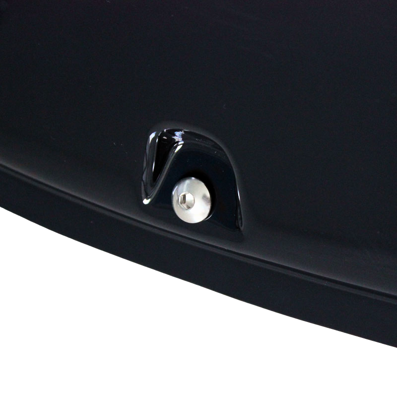 A metallic button surrounded by glossy black material is embedded in a dark, smooth surface, suggesting part of a vehicle's exterior.