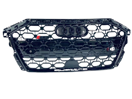 A black car grille with a honeycomb pattern displaying the Audi logo, "RS 5," and "quattro" text, against a plain white background.