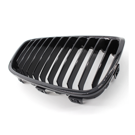 A black car grille with vertical slats rests on a white surface, showcasing its glossy finish and sleek design.