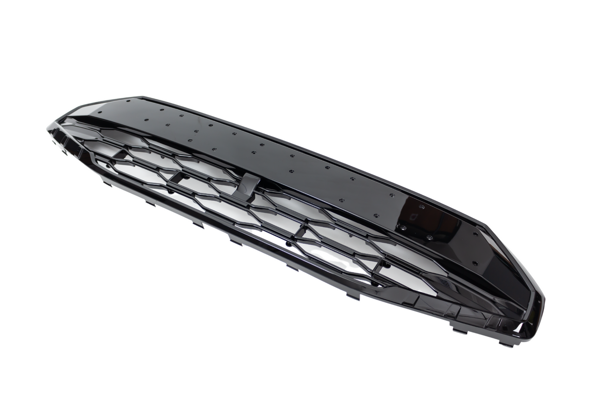 A glossy black automotive grille with a hexagonal mesh pattern lies angled, isolated against a plain white background, highlighting its shiny surface and angular edges.