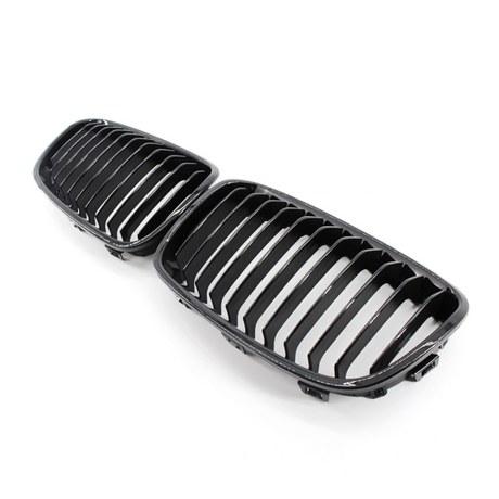 A pair of black, glossy car grilles featuring vertical slats, positioned side by side on a plain white background.