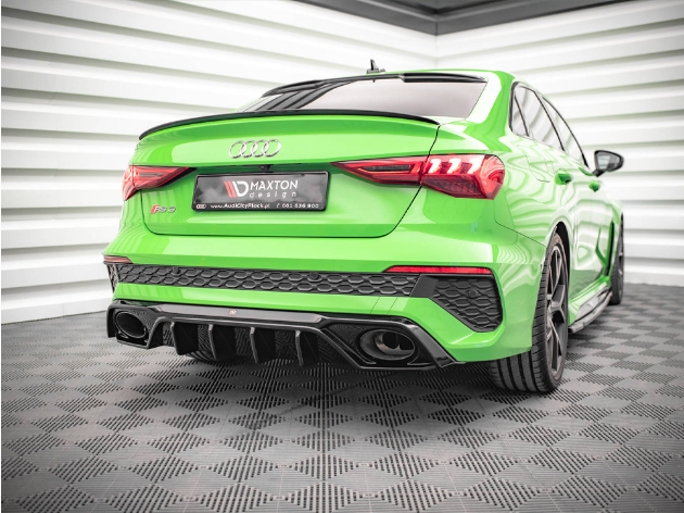A vibrant green Audi RS3 is parked, showcasing its rear with a black diffuser, dual exhausts, and branding. The context is a geometric garage space with patterned flooring. Identifier text: "MAXTON."