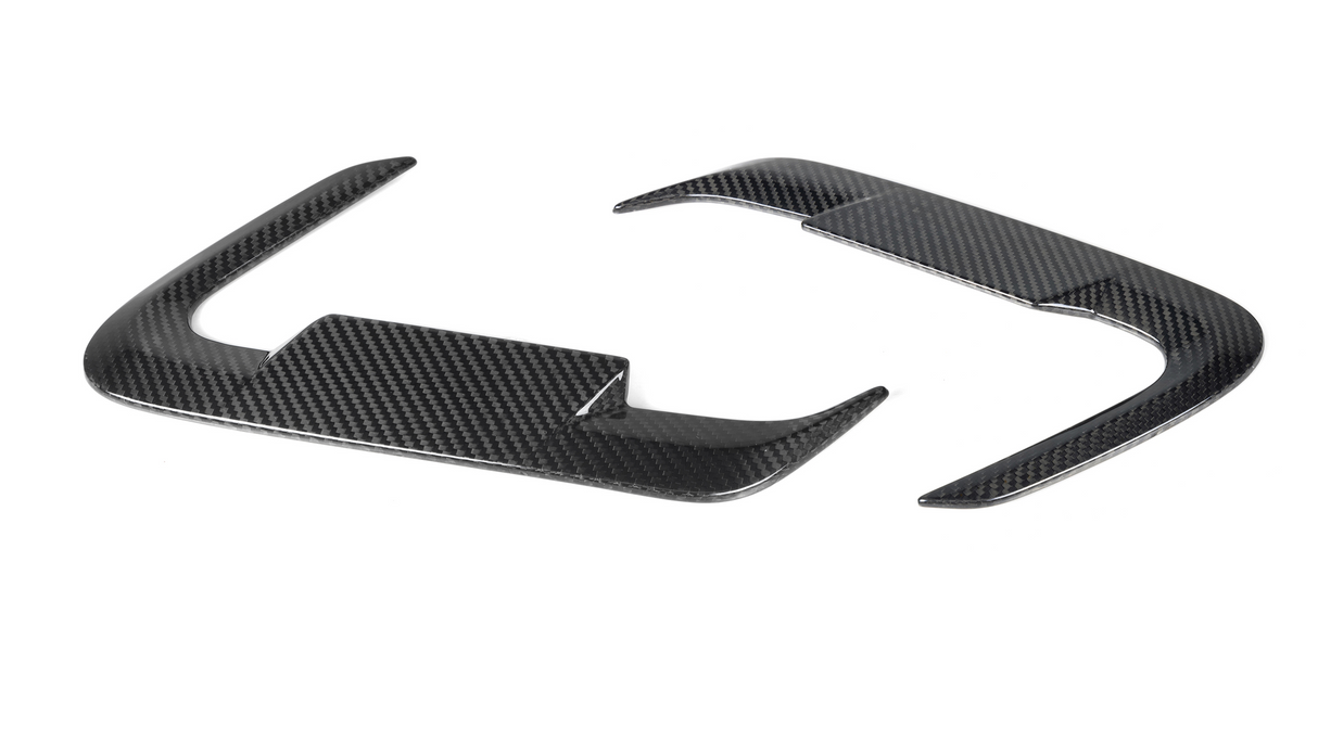 Carbon fiber steering wheel trim pieces, curved and glossy, rest on a plain white background.