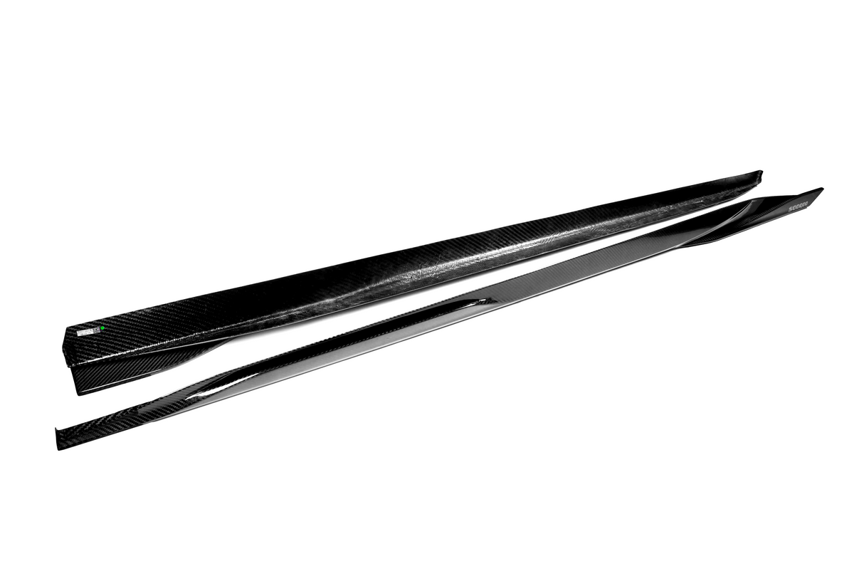 Two sleek, black carbon-fiber side skirts lie parallel on a white background, showcasing their smooth, aerodynamic design ideal for automotive enhancements.