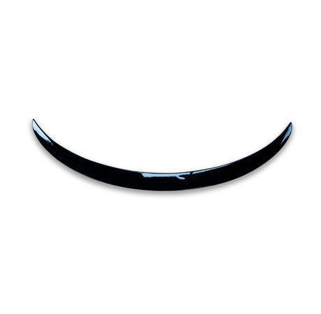 A shiny, curved black object resembling a crescent is positioned against a plain white background, giving a minimalist and modern appearance.