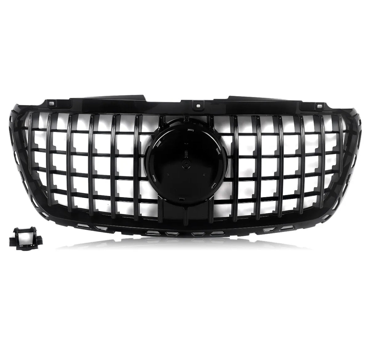 A black car grille features a grid design with a central circular emblem area, set against a white background. A detached rectangular component is located in the lower left corner.