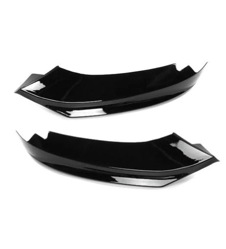 Two black, glossy aerodynamic car accessories lie side by side against a plain white background, showcasing their smooth, curved design and angular edges.