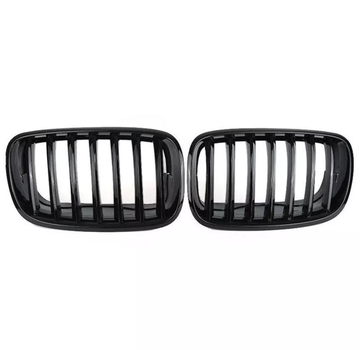 Two black car grilles with vertical slats are displayed side by side against a plain white background, showcasing a sleek automotive accessory design.