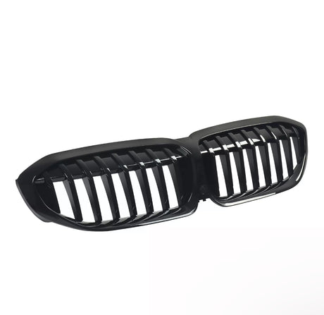 A shiny black car grille features dual kidney-shaped openings with vertical slats, presented against a plain white background.