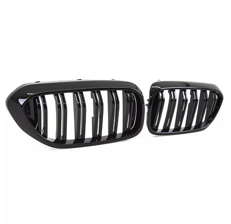 Two glossy black car grilles, featuring vertical slats, are positioned against a plain white background, highlighting their sleek and modern design.
