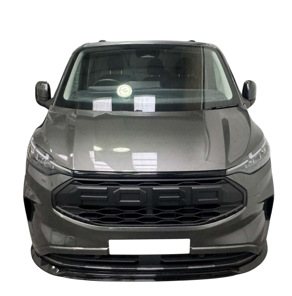 A gray vehicle stands facing forward, displaying its sleek front grille and headlights, in front of a solid black background. Reflections are visible on the windshield.