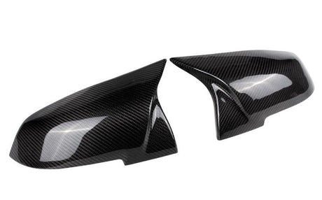 Two carbon fiber car mirror caps are displayed side by side on a plain white background, showcasing their glossy, textured finish and sleek aerodynamic design.