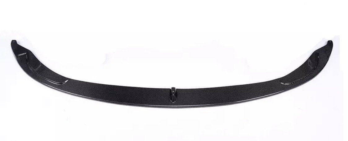 A curved carbon fiber car spoiler lies against a plain white background, showcasing its sleek, aerodynamic design with a textured surface and smooth edges.