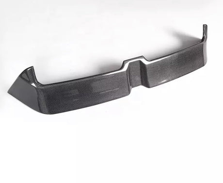 A carbon fiber car bumper sits on a white background, showcasing a sleek, angular design with a textured surface and raised edges.