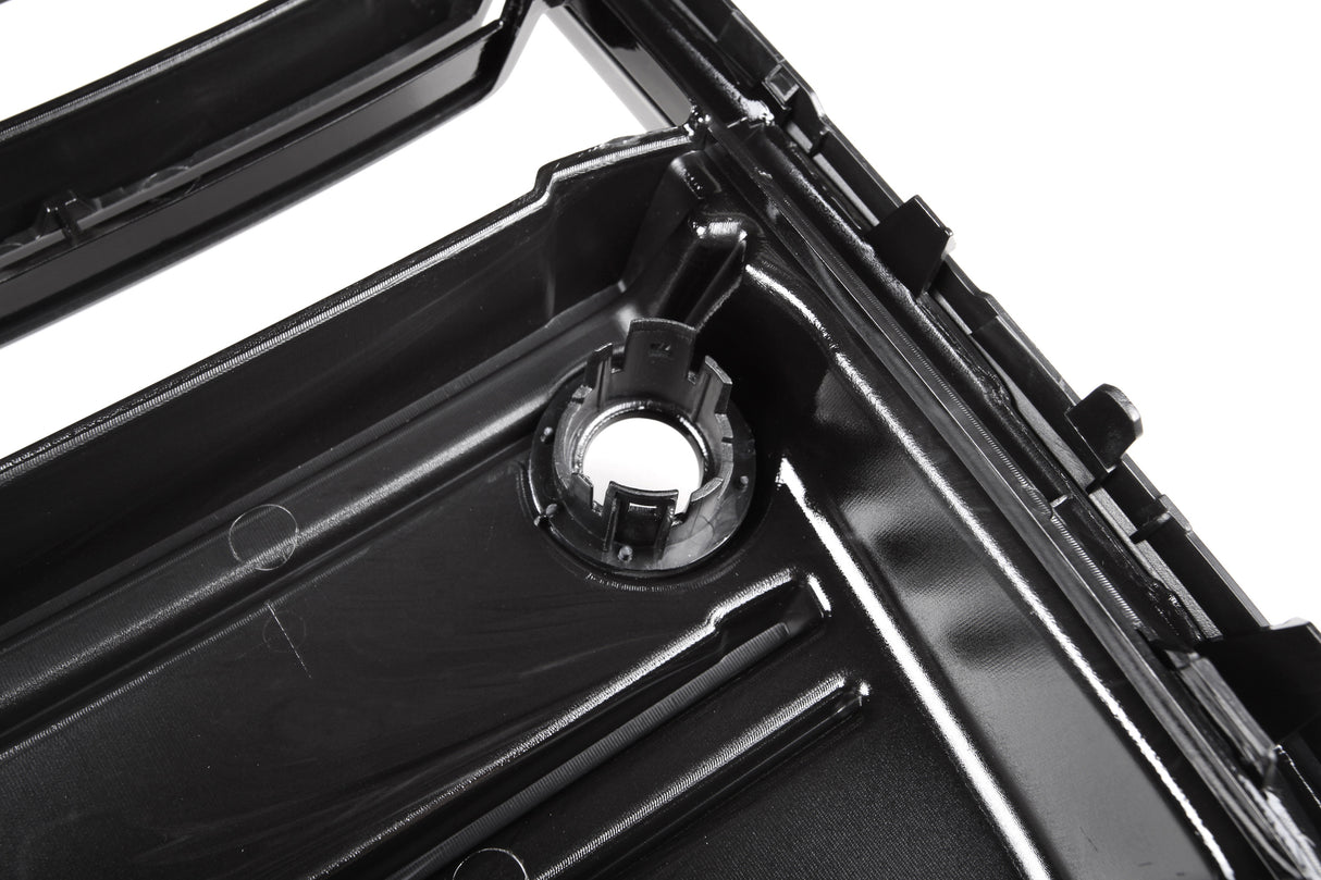 A glossy black plastic automotive part with a circular mount and ridges is shown in close-up, likely part of a larger engine or mechanical assembly.